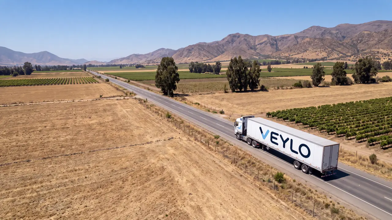 Camión con remolque de Veylo en una ruta recta, con la cordillera al fondo.